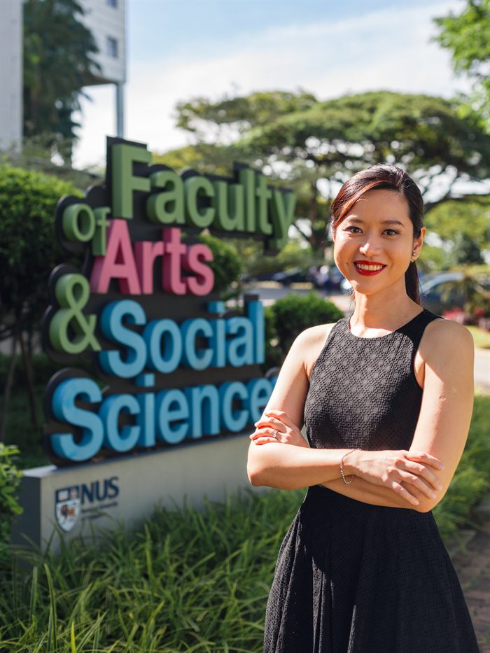 Nala H. Lee standing beside the Faculty of Arts and Social Sciences sign at the National University of Singapore